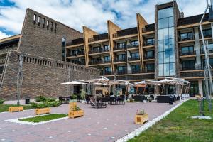 a building with tables and umbrellas in front of it at Shahdag Hotel & Spa in Shahdag
