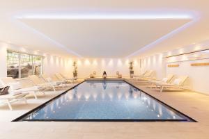 a swimming pool in a room with chairs and a table at Parkhotel Schachen in San Giovanni in Val Aurina