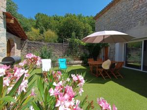 um pátio com uma mesa, cadeiras e um guarda-sol em Maison sur le Lot em Saint-Vincent-Rive-dʼOlt