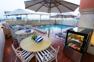 eine Terrasse mit Tischen und Sonnenschirmen und einem Pool in der Unterkunft Al Hamra Hotel in Schardscha