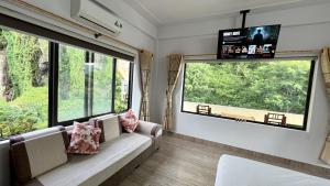 a living room with a couch and two large windows at Thao Nguyen Homestay in Phong Nha