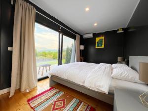 1 dormitorio con cama grande y ventana grande en FLANDRA Glamping, en Corbeni