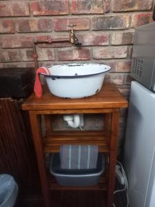 a white bowl on a wooden table with a sink at Earthbound Guest House in Oudtshoorn