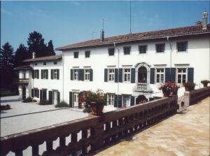 een groot wit gebouw met bloemen ervoor bij Volpe Pasini - Wine and Rooms in Togliano