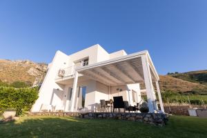 a white house with a porch and a lawn at Villa Cristina - Relax - Piscina e Vista Mare in Castellammare del Golfo