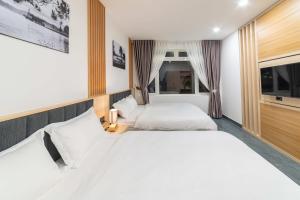 a bedroom with two beds and a window at Quốc Khánh Condotel in Da Lat