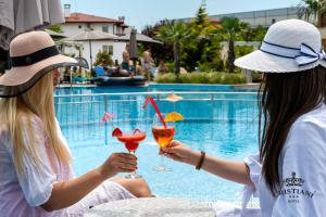duas mulheres a beber cocktails em frente a uma piscina em Cristiani Hotel Sozopol em Sozopol