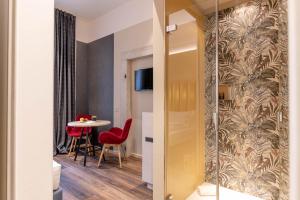 Habitación con mesa, sillas rojas y mampara de cristal en Calepina Alpine Suite en Trento