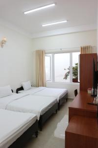 um quarto com 2 camas, uma secretária e uma janela em Mây Đà Lạt Home em Da Lat