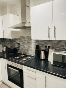 a kitchen with white cabinets and a black counter top at Superb and Comfortable 3BD Home in Dagenham in Dagenham