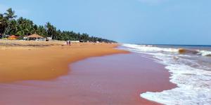 a beach with the ocean and people walking on it at Hotel Sunday - Townhouse Club Airport Trivandrum in Trivandrum