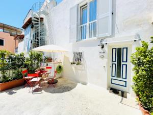 une terrasse avec une table, des chaises et un parasol dans l'établissement Blue Apartment, à Ischia