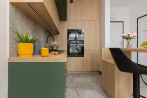 a kitchen with wooden cabinets and a black appliance at Home Factory Estate Praga Kotsisa by Renters in Warsaw