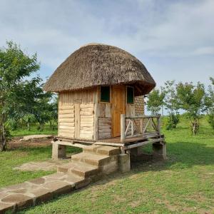 małą chatę z dachem krytym strzechą i ławką w obiekcie Songbird Safari Lodge & Campsite w mieście Katunguru
