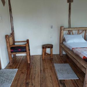 Songbird Safari Lodge & Campsite في Katunguru: غرفة نوم بسرير وكرسي وأرضيات خشبية