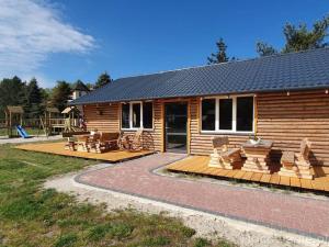 a log cabin with a deck and a playground at Domki Pod Lasem in Mrzeżyno