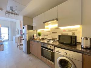 a kitchen with a washer and a stove and a microwave at Mira Holiday Homes - Serviced studio with balcony in Dubai