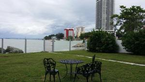 une table et des chaises assises sur une pelouse près de l'eau dans l'établissement Beach Front Bungalow Tanjung Bungah, à George Town