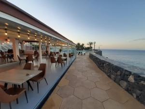 a restaurant with tables and chairs next to the ocean at Westhaven Bay in Costa Del Silencio