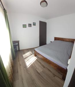 a bedroom with a bed and a wooden floor at Cabana PUFI in Dobîrlău