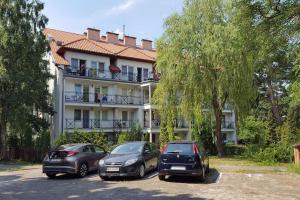 three cars parked in a parking lot in front of a building at Apartament Teresa Krynica Morska in Krynica Morska