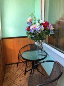 um vaso de flores sentado numa mesa com duas cadeiras em KULDIGAS 38 APARTMENTS em Liepāja