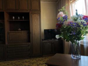 een vaas met bloemen op een tafel in een kamer bij KULDIGAS 38 APARTMENTS in Liepāja