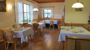 restauracja z białymi stołami, krzesłami i oknami w obiekcie Gästehaus Am Ludwigsberg w mieście Bad Kötzting
