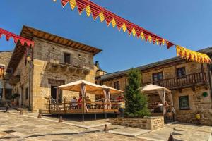 ein Gebäude mit Tischen und Sonnenschirmen davor in der Unterkunft La Hoja de Roble in Puebla de Sanabria