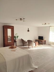 Cette chambre blanche comprend un lit, des chaises et une télévision. dans l'établissement Maison Caiada, à Urrugne