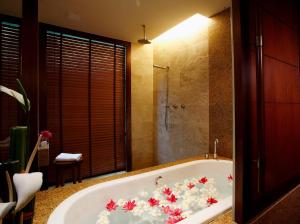 Centara Grand Beach Resort & Villas Krabi في شاطيء آونانغ: حمام مع حوض استحمام مملوء بالورود