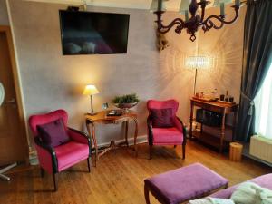 a living room with two chairs and a table at Au trou perdu in Corroy-le-Château