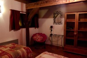 een slaapkamer met een bed, een spiegel en een stoel bij Gite les Cigognes in Neuwiller-lès-Saverne