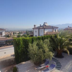 a view of a resort with two chairs and palm trees at Villa 28 de julio Casa Rural con piscina en Granada in Granada