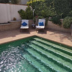 2 sillas sentadas junto a una piscina en Villa 28 de julio Casa Rural con piscina en Granada en Granada