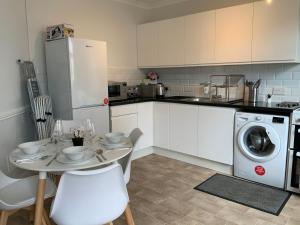 a kitchen with a table and a washing machine at Stylish 2 Bedroom Cottage in Bishop's Stortford by BookedUK in Stansted Mountfitchet