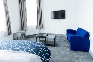 a bedroom with a bed and a blue chair and a tv at Empress House in Manchester