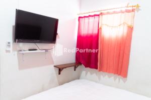 um quarto com uma televisão de ecrã plano e uma cama em Wisma Narada 2 Lampung Mitra RedDoorz em Tanjungkarang