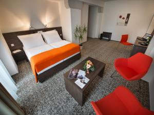 une chambre d'hôtel avec un lit et un fauteuil rouge dans l'établissement EA Business Hotel Jihlava, à Jihlava