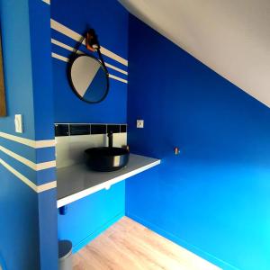 ein blaues Badezimmer mit einem Waschbecken und einem Spiegel in der Unterkunft Maison bretonne au cœur d'un petit hameau 