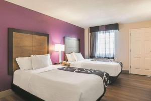 2 Betten in einem Hotelzimmer mit lila Wänden in der Unterkunft Wingate by Wyndham Galveston East Beach in Galveston