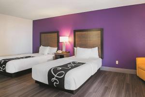 um quarto de hotel com duas camas e uma parede roxa em Wingate by Wyndham Galveston East Beach em Galveston