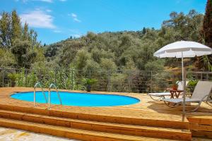 a wooden deck with a pool and an umbrella at Villa Amfiliki in Kavalléraina