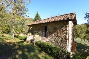 a stone house with a porch in a field at Vignoli in Bagni di Lucca