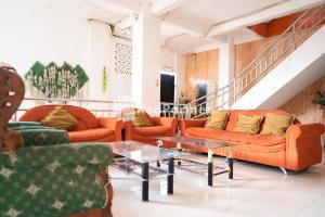 uma sala de estar com sofás laranja e uma mesa de vidro em Hotel Ratu Ayu 2 Lampung Mitra RedDoorz em Tanjungkarang