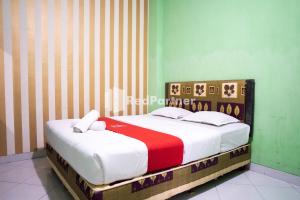 um quarto com uma cama com um cobertor vermelho e branco em Hotel Ratu Ayu 2 Lampung Mitra RedDoorz em Tanjungkarang