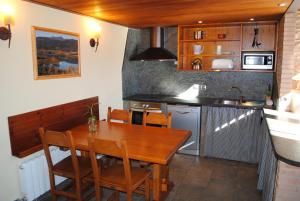 a kitchen with a wooden table with chairs and a sink at La Cabanya in Porqueres