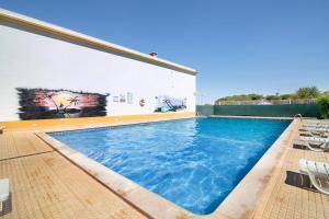 a large swimming pool with chairs and a building at Ae Flat Falesia in Albufeira