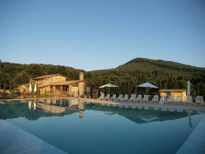 a swimming pool with chairs and a house and mountains at Residenza di Rocca Romana Holiday Home in Trevignano Romano