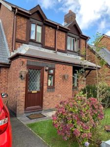 a brick house with a brown door and flowers at Spacious 2 BR home close to town & coast + parking in Uzmaston